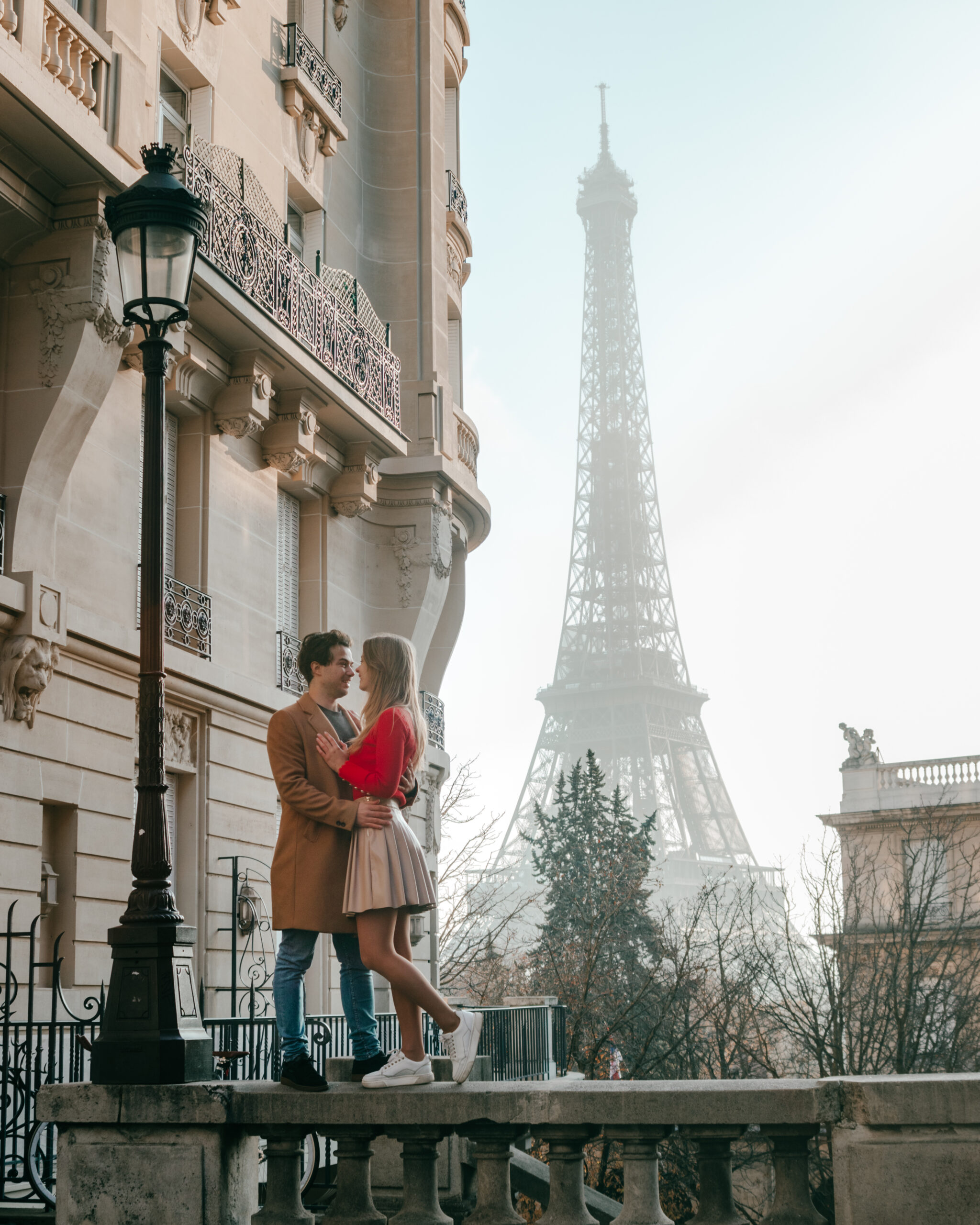 Couple trip in Paris standing in Avenue de Camoens with view on the Eifel Tower
