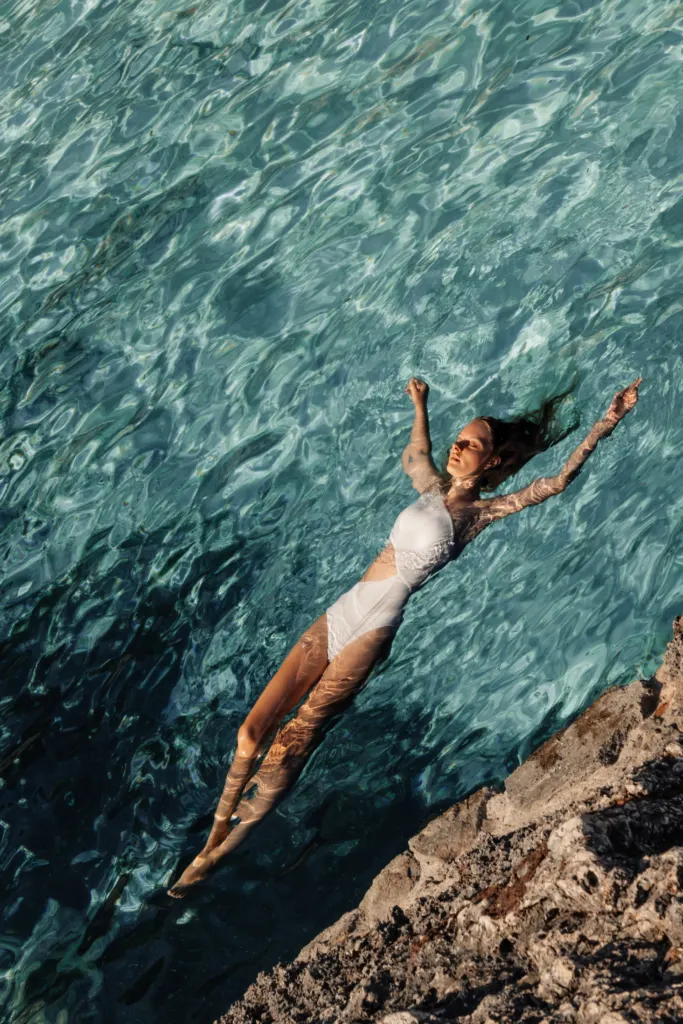 Swimmer seen from above in turquoise water between the rocks