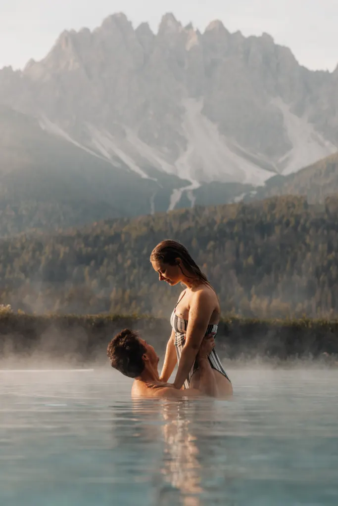 Woman in a misty infinity pool facing the Dolomites