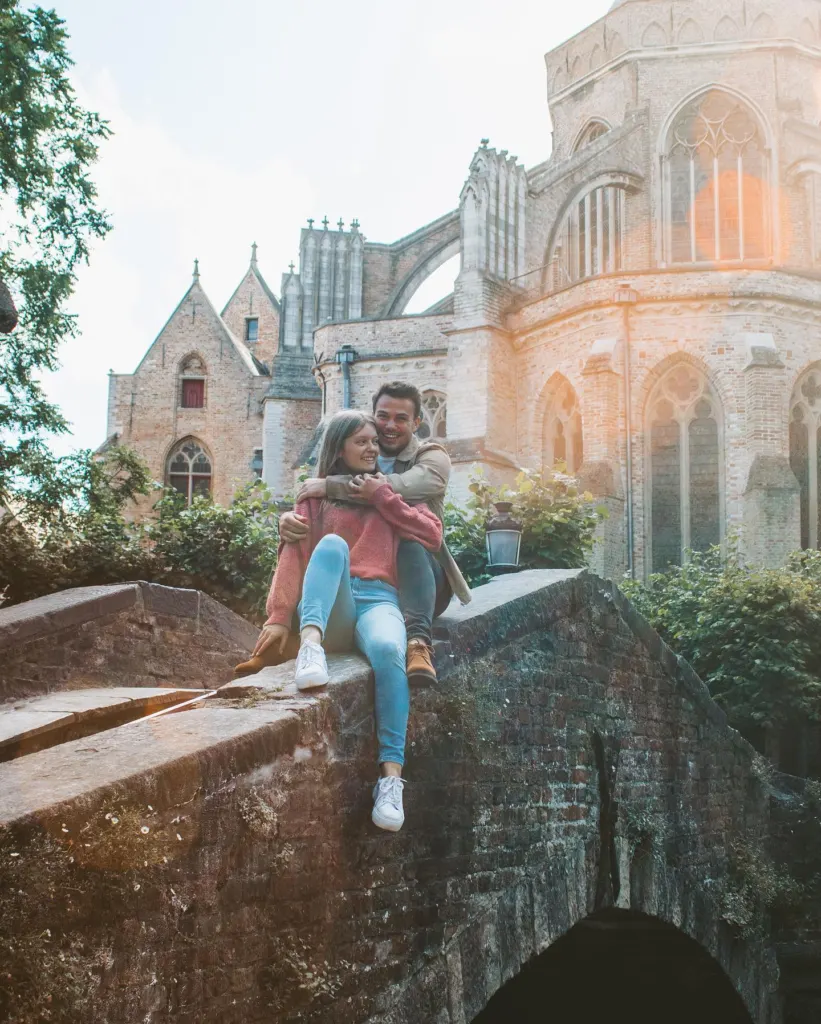 Couple sitting on the stone Bonifacius bridge in Bruges