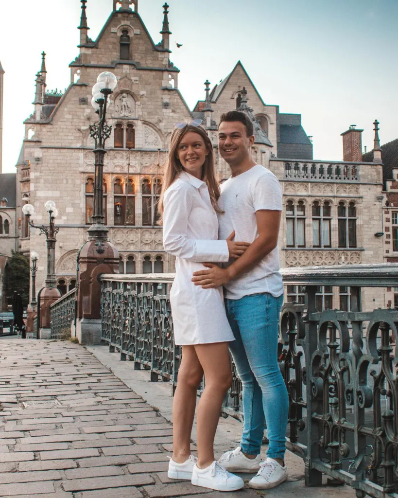 Couple standing at a railing along the Ghent canal with gabled guild houses behind