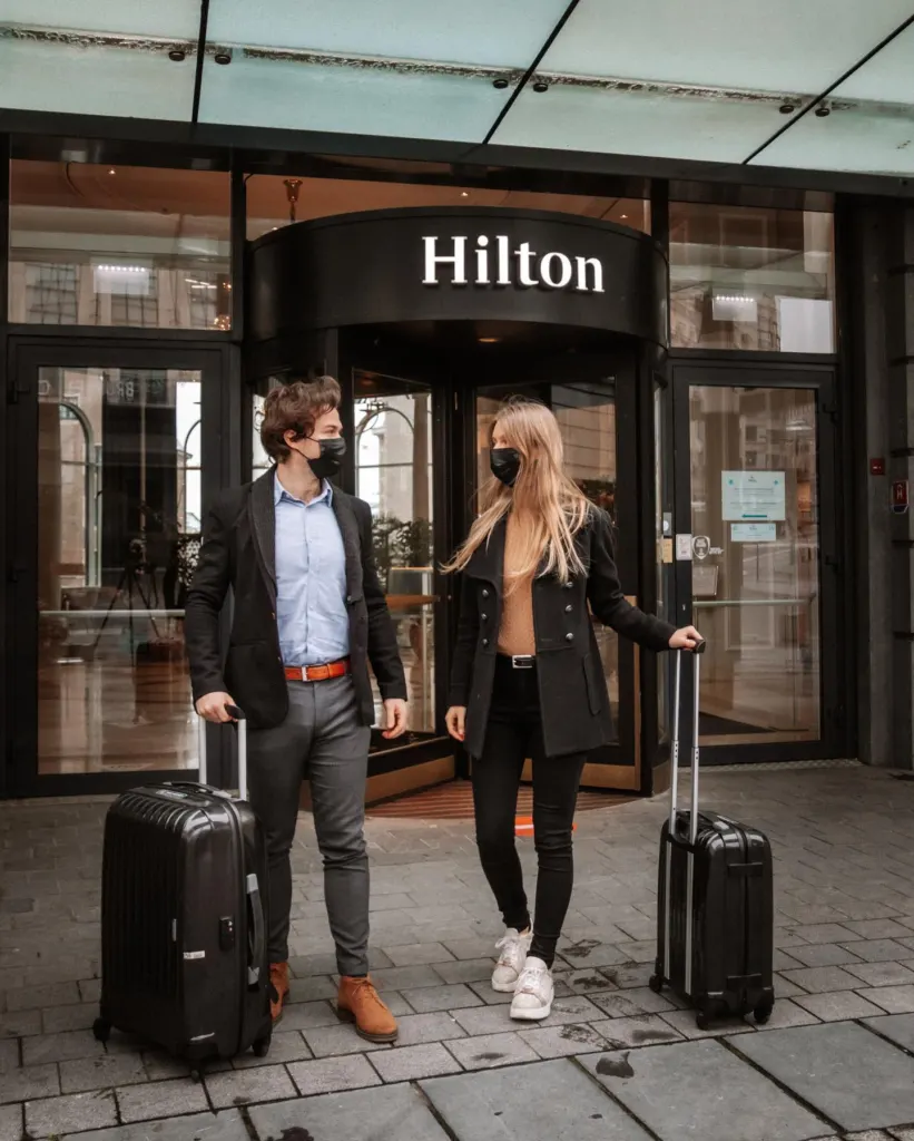 Couple with suitcases in front of the Hilton Brussels Grand Place entrance