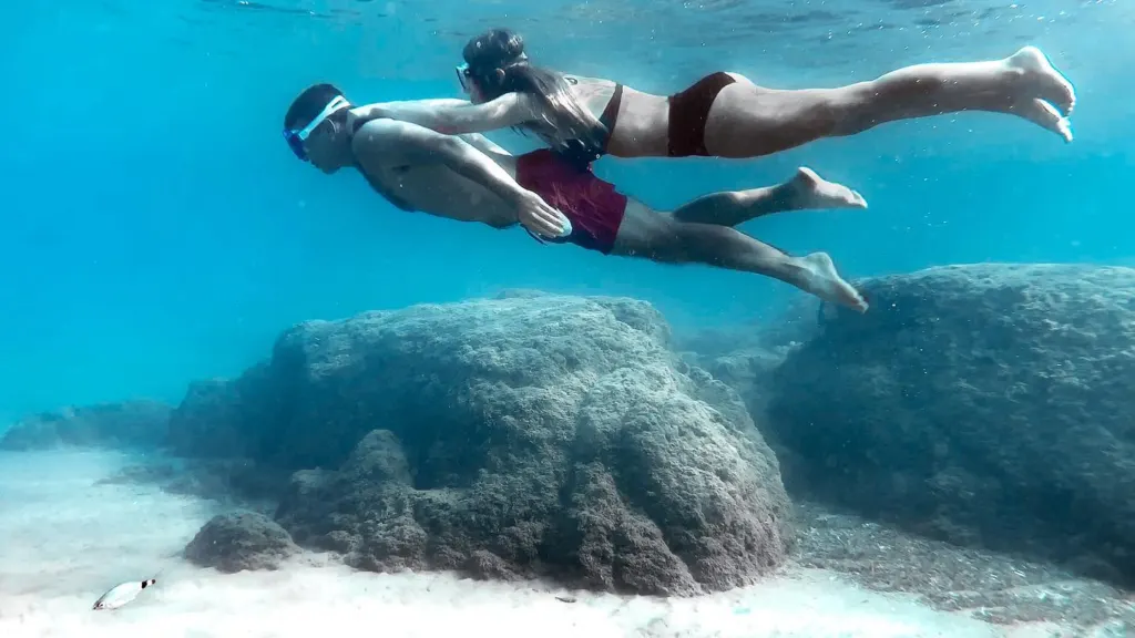 Woman swimming underwater above rocks in the clear sea off Kos