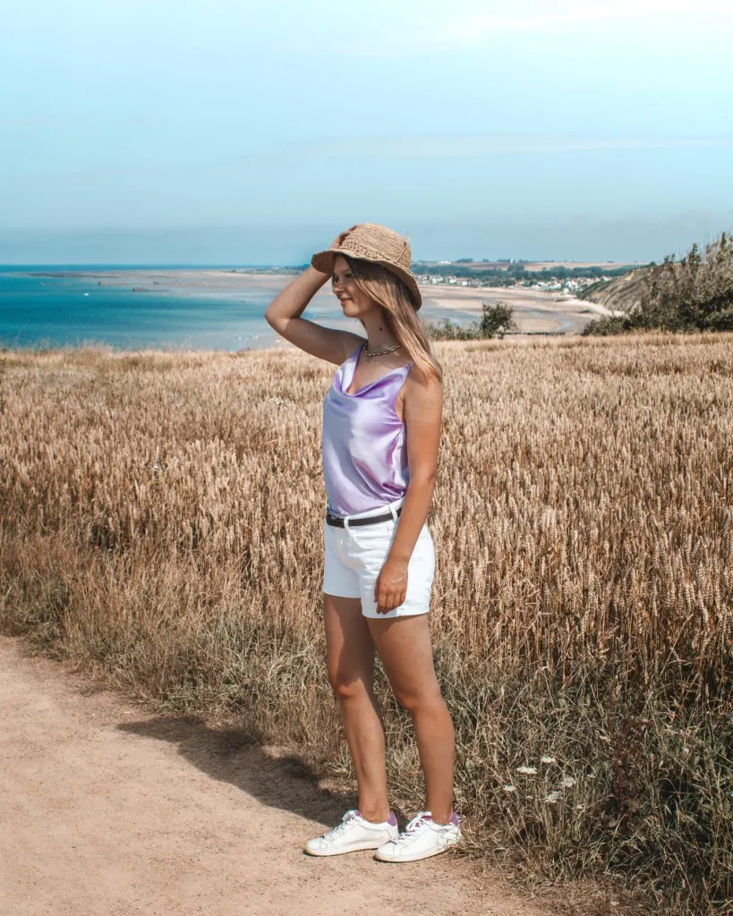 Woman in a sun hat on a grassy coastal path in Normandy